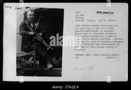 Le sergent-major Owen J. Furuseth de l'Escadron d'observation maritime-6 se prépare pour sa prochaine mission à bord de l'hélicoptère de combat Uh-1E Huey. Basé à l'aérodrome de Quang Tri, Furuseth sert de sergent-major de l'escadron et s'est porté volontaire comme mitrailleur Huey sur 47 missions. Cette photo a été prise le 30 avril 1968, pendant les opérations de la guerre du Vietnam. Banque D'Images