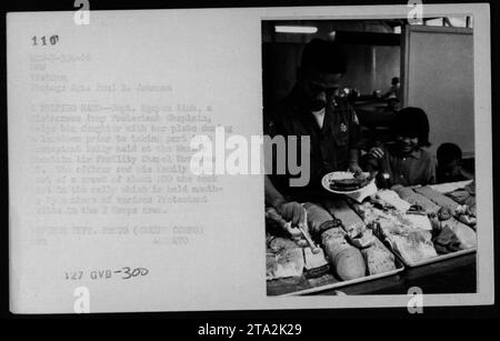 Le capitaine Nguyen LanH, un aumônier protestant, a aidé sa fille avec son assiette lors d'un déjeuner tenu à la chapelle de l'installation aérienne de Marble Fountain en novembre 1966. Ce rassemblement, auquel ont participé environ 200 personnes, a été organisé par divers groupes protestants dans la région du Ier corps, démontrant le soutien du personnel militaire et de leurs familles pendant la guerre du Vietnam. (Photographe : Sgt. Paul E. Jolazion) Banque D'Images