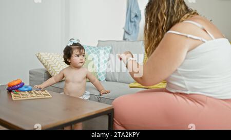 Mère et fille profitent d'une belle journée à l'intérieur, assis sur leur canapé de salon, s'engageant de manière ludique dans un jeu de cerceaux à la maison, fusionnant l'esprit de jeu Banque D'Images