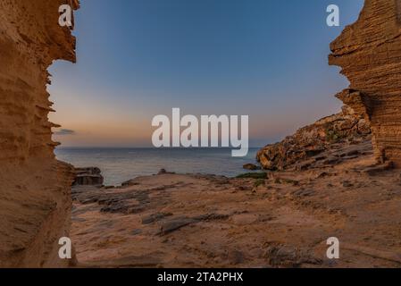 Grottes creusées dans le tuf jaune dans la falaise de Bue Marino aux premières lumières du matin, Favignana Banque D'Images