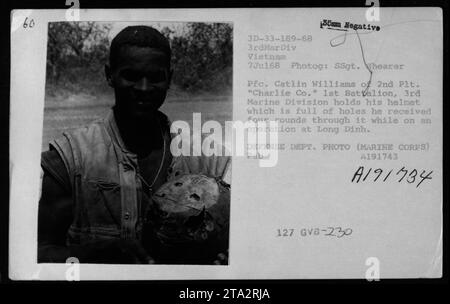 Le 7 juillet 1968, le PFC Catlin Williams du 2e peloton, Charlie Company, 1er bataillon, 3e division des Marines tient son casque criblé de quatre trous de balles provenant d'une opération à long Dinh, au Vietnam. Banque D'Images