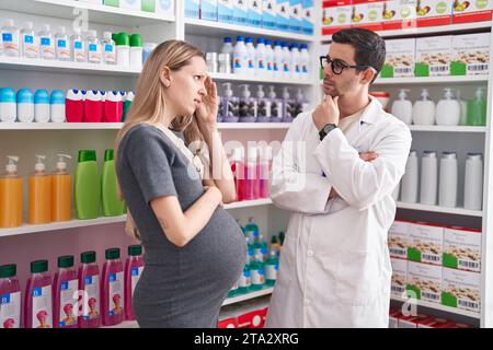 Homme et femme pharmacien et cliente enceinte parlant à la pharmacie Banque D'Images