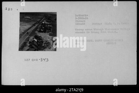 Un convoi composé de divers véhicules, y compris des jeeps, des mules, des camions et des buggies sur les dunes, se déplace à travers un village vietnamien sur son chemin vers Danang depuis Chuted. La photographie a été prise le 18 décembre 1966, pendant la guerre du Vietnam, par le caporal A. Lowes de la 3e Division des Marines. C'est une photo du ministère de la Défense prise par Marie Cores. Banque D'Images