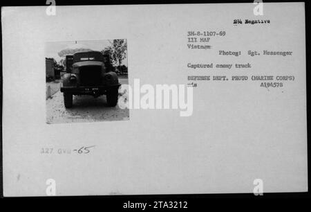 Cette photographie en noir et blanc montre la vue de face d'un camion ennemi capturé pendant la guerre du Vietnam. La photographie capture divers engins, y compris de la nourriture, des drapeaux et des fournitures, qui ont été saisis à l'ennemi. L'image porte le numéro d'identification 3M-8-1107-69 III MAF Vietnam, et elle a été prise par le sergent Messenger, un photographe militaire. C'est une photo du ministère de la Défense avec l'identifiant A194578. Banque D'Images