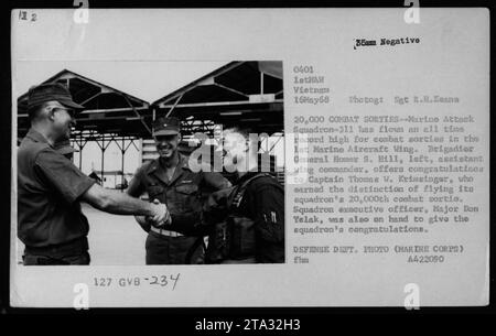 Marine Attack Squadron-311 réalise un record de 20 000 sorties de combat pendant la guerre du Vietnam. Le brigadier général Homer S. Hill félicite le capitaine Thomas W. Krimsinger pour avoir piloté la 20 000e sortie de combat de l'escadron. Le major Don Yelak, officier exécutif de l'escadron, se joint à lui pour offrir ses félicitations. Cette image capture la célébration de cette étape importante dans les activités militaires américaines pendant la guerre. Banque D'Images