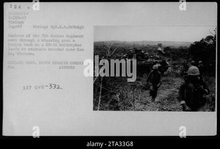 Les membres du 9e Régiment de Marines passent par une clairière devant un char des Marines alors qu'un hélicoptère CH-46 atterrit pour évacuer les blessés près de CEM Lo, au Vietnam. Prise le 7 avril 1967, cette photographie capture les activités militaires américaines pendant la guerre du Vietnam. DEPT. DÉFENSE PHOTO (MARINE CORPS) A188592 127 GVB-332. Banque D'Images