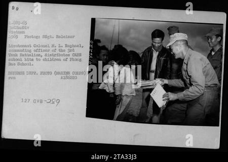 Le lieutenant-colonel M. L. Raphael, commandant du 3e bataillon de chars, distribue des kits scolaires DE SOINS aux enfants de l'école Phong bac en 1965. Cette image montre une interaction de peuple à peuple entre l'armée américaine et les civils vietnamiens pendant la guerre du Vietnam. Photographie par SSgt. Releiser, photo du Département de la Défense. Banque D'Images