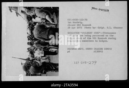 Des réfugiés vietnamiens sont vus en cours de traitement sur le pont d'envol de l'USS Hancock lors d'exercices d'évacuation à Saigon dans le cadre de l'opération Frequent Wind le 29 avril 1975. Cette photographie, prise par GySgt. D.L. Shearer, capture un moment de la mission d’évacuation effectuée par le 1st MarBrig. Banque D'Images