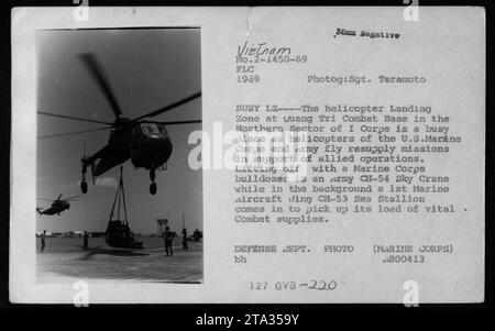 L'image montre une zone d'atterrissage d'hélicoptère animée à la base de combat de Quang Tri dans le I corps, Vietnam en 1969. Un hélicoptère CH-54 Sky Crane de l'Armée de terre est vu décoller avec un bulldozer du corps des Marines, tandis qu'en arrière-plan, un CH-53 Sea Stallion de la 1st Marine Aircraft Wing atterrit pour ramasser des fournitures de combat essentielles. Cette photographie a été prise par le sergent Teramoto et fait partie des archives du Département de la Défense. Banque D'Images