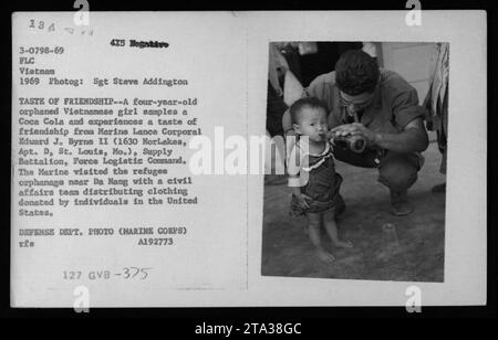 La jeune orpheline vietnamienne prend sa première gorgée de Coca Cola et partage un moment de camaraderie avec le caporal lance des Marines Edward J. Byrna. Le Marine, qui fait partie d'une équipe des affaires civiles, a apporté des dons de vêtements des États-Unis à l'orphelinat de réfugiés près de Da Nang. Prise en 1969 pendant la guerre du Vietnam. Banque D'Images