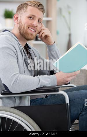 homme handicapé sur un livre de lecture pour fauteuil roulant Banque D'Images