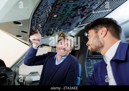 enseignant montrant à l'apprenti les commandes aériennes dans le cockpit de l'avion Banque D'Images