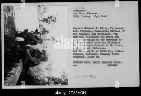 Le capitaine Michael F. Welty de la Fox Company, 2e bataillon, 7e Marines, et le lieutenant-colonel L. N. Utter discutent d'une opération de balayage et de dégagement à l'entrée de Cu Mong Hamlet. Le 1e sergent E. J. McCarthy observe le briefing mené par le commandant et son commandant de bataillon lors de la tournée de 1965 à qui Nhon, au Vietnam. Banque D'Images