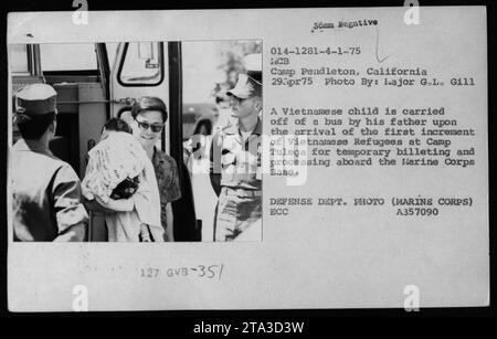 Enfant vietnamien arrivant avec son père au Camp Tulega, un centre temporaire de réception et de traitement pour les réfugiés vietnamiens le 29 avril 1975. La photo montre le premier groupe de réfugiés arrivant au camp de base du corps des Marines Pendleton en Californie. Cette image a été prise par Hajor G.L. Gill, un photographe officiel du ministère de la Défense. Banque D'Images