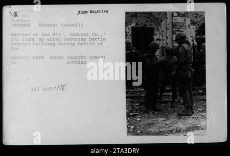 Les Marines du 2e peloton, Foxtrot Company, 2/5, s'allument après avoir réussi à sécuriser un bâtiment lors de la bataille intense de la ville de Hue le 18 février 1968. Cette photographie a été prise par Casselli et est un négatif 35mm de la collection MAP Vietnam. Il a été officiellement publié et est attribué au ministère de la Défense. Banque D'Images