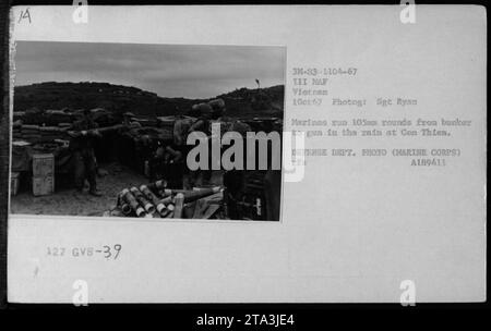 Les Marines à con Thien courent des balles de 105 mm à travers la pluie depuis un bunker jusqu'à un canon pendant la guerre du Vietnam. La photographie, prise le 1 octobre 1967, montre le processus de chargement et de déchargement des munitions. Cette image illustre la détermination et la résilience des troupes américaines dans des conditions difficiles. Banque D'Images