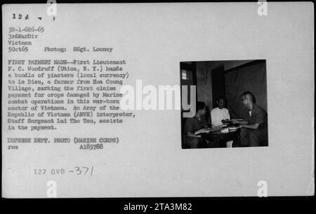 Le premier lieutenant F. C. Woodruff d'Utica, N.Y., effectue le premier paiement pour les récoltes endommagées par les opérations de combat des Marines au Vietnam. Il remet un paquet de monnaie locale, des piasters, à le Dieu, un agriculteur du village de Hoa Coung. Le sergent d'état-major Lai the Tam, interprète de l'armée de la République du Vietnam, aide au paiement.' Banque D'Images