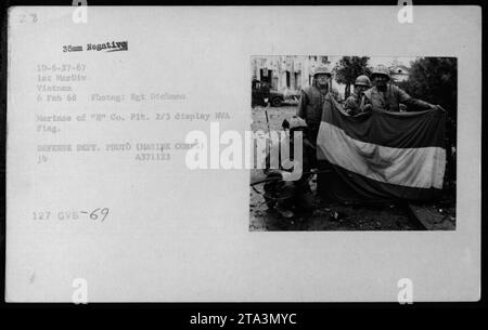 Les Marines du peloton 2/5 de la compagnie arborent fièrement un drapeau de la NVA capturé pendant la guerre du Vietnam. Cette photographie a été prise le 6 février 1968 par le sergent Dickman de la 1e Division des Marines. L'image montre les Marines présentant le butin de guerre, soulignant la capture d'armes ennemies et symbolisant leurs activités militaires réussies. Banque D'Images