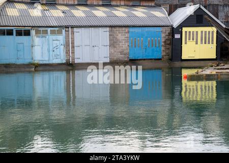 Portes colorées des maisons de bateau le long de Batson Creek avec leurs reflets vus dans la marée haute de l'eau dans le ruisseau. Banque D'Images