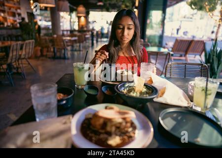 Adolescente asiatique mangeant de la nourriture mexicaine dans un restaurant dans l'après-midi Banque D'Images