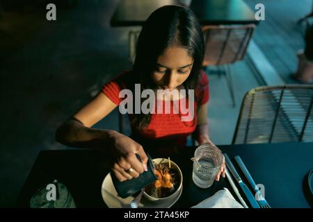 Adolescente asiatique mangeant de la nourriture mexicaine dans un restaurant dans l'après-midi Banque D'Images