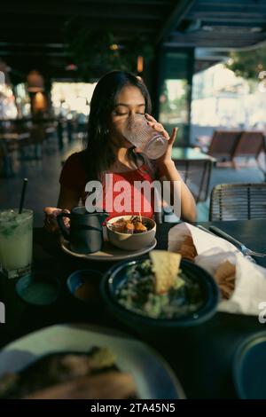 Adolescente asiatique mangeant de la nourriture mexicaine dans un restaurant dans l'après-midi Banque D'Images