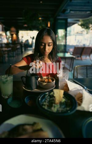 Adolescente asiatique mangeant de la nourriture mexicaine dans un restaurant dans l'après-midi Banque D'Images