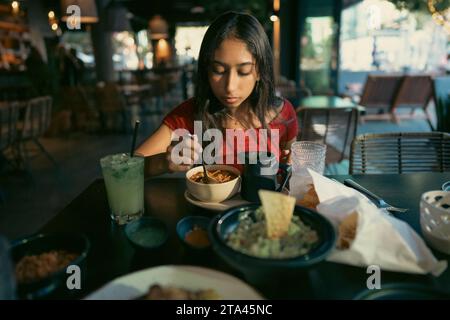 Adolescente asiatique mangeant de la nourriture mexicaine dans un restaurant dans l'après-midi Banque D'Images