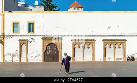 Essaouira, Maroc - 17 septembre 2022 : Femme marocaine marchant dans la vieille ville médina d'Essaouira, avec l'architecture marocaine traditionnelle en arrière-plan Banque D'Images