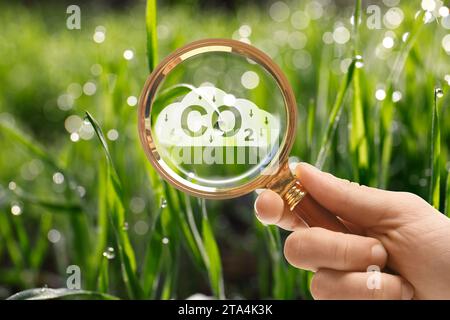 Réduire les émissions de CO2. Femme démontrant l'inscription de CO2 à travers une loupe à l'extérieur, gros plan Banque D'Images