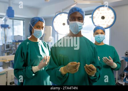 Portrait de divers chirurgiens masculins et féminins avec des masques faciaux en salle d'opération hospitalière Banque D'Images