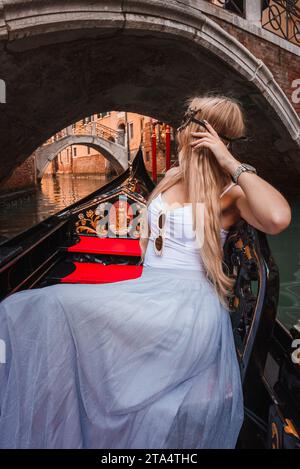 Femme sereine profitant d'une promenade en gondole à travers les canaux pittoresques de Venise, Italie Banque D'Images