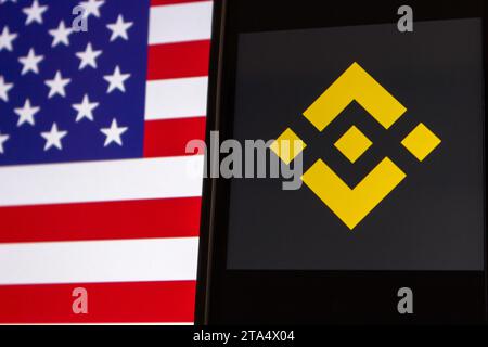 Vancouver, CANADA - novembre 28 2023 : logo Binance vu sur l'écran de l'iPhone sur fond de drapeau américain. Binance est la plus grande plateforme d'échange de crypto-monnaie Banque D'Images