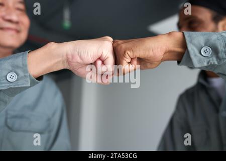 Les constructeurs se donnent mutuellement la première bosse après avoir terminé le quart de travail sur le chantier de construction Banque D'Images