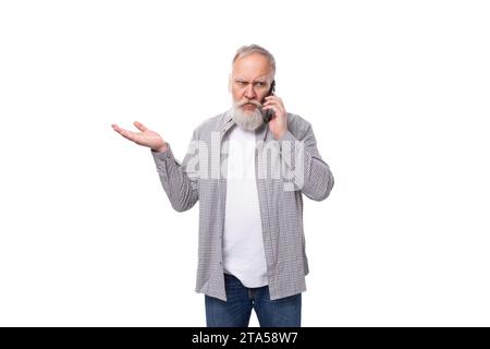 mignon grand-père intelligent avec une barbe blanche et une moustache vêtue d'une chemise rayée sur un t-shirt parle au téléphone Banque D'Images