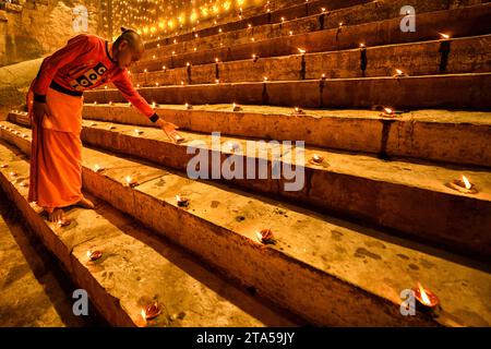 Varanasi, Inde. 27 novembre 2023. Un enfant moine allume des lampes à la veille de Dev Deepavali. Dev Deepavali, également connu sous le nom de Diwali des Dieux, est un festival célébré sur Karthik Purnima, qui tombe 15 jours après Diwali. Dev Deepavali est le plus grand festival de lumière de l'Inde où les dévots décorent la rive du Gange avec des millions de lampes dans le cadre du festival. (Photo Avishek Das/SOPA Images/Sipa USA) crédit : SIPA USA/Alamy Live News Banque D'Images