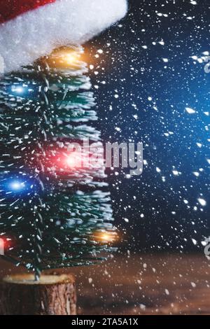 Arbre de Noël avec guirlande est décoré avec fond de chapeau de Père Noël tombant de la neige Banque D'Images
