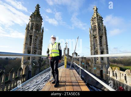 Stephen Cherry, doyen de King's College Chapel, voit l'installation de 438 nouveaux panneaux solaires photovoltaïques sur le toit de la chapelle récemment restaurée du King's College Cambridge. Les panneaux répondront à 100 % des besoins énergétiques de la Chapelle et réduiront les émissions de carbone du Collège de plus de 27 tonnes par an. Date de la photo : mardi 28 novembre 2023. Banque D'Images