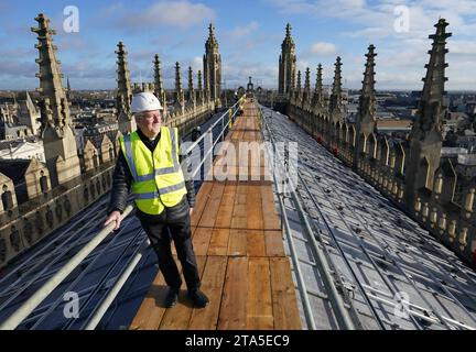 Stephen Cherry, doyen de King's College Chapel, voit l'installation de 438 nouveaux panneaux solaires photovoltaïques sur le toit de la chapelle récemment restaurée du King's College Cambridge. Les panneaux répondront à 100 % des besoins énergétiques de la Chapelle et réduiront les émissions de carbone du Collège de plus de 27 tonnes par an. Date de la photo : mardi 28 novembre 2023. Banque D'Images