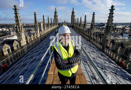 Stephen Cherry, doyen de King's College Chapel, voit l'installation de 438 nouveaux panneaux solaires photovoltaïques sur le toit de la chapelle récemment restaurée du King's College Cambridge. Les panneaux répondront à 100 % des besoins énergétiques de la Chapelle et réduiront les émissions de carbone du Collège de plus de 27 tonnes par an. Date de la photo : mardi 28 novembre 2023. Banque D'Images