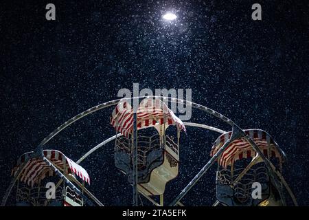 Hanovre, Allemagne. 29 novembre 2023. Une grande roue se tient tôt le matin à un marché de Noël sur Ernst-August-Platz en face de la gare principale dans de fortes chutes de neige. Crédit : Moritz Frankenberg/dpa/Alamy Live News Banque D'Images