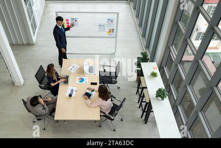 Un environnement de bureau montre un groupe de personnes assis autour d'une table, apparemment impliqués dans une discussion d'affaires sérieuse. Banque D'Images