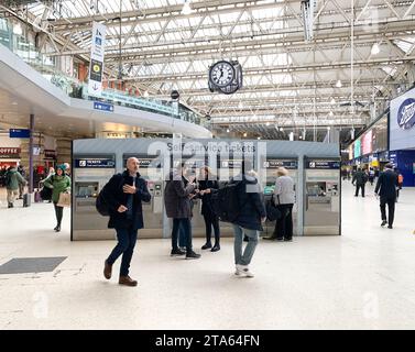 Waterloo, Londres, Royaume-Uni. 27 novembre 2023. Passagers utilisant des distributeurs automatiques de billets en libre-service à la gare de Waterloo à Londres. Les membres du syndicat des conducteurs ASLEF organiseront une autre série de grèves d’une journée entre les différents opérateurs ferroviaires entre le 2 décembre 2023 et le 8 décembre 2023. Il y aura également une interdiction des heures supplémentaires dans toutes les compagnies ferroviaires du 1 au 9 décembre 2023 dans un différend amer en cours sur les salaires et les conditions. Crédit : Maureen McLean/Alamy Live News Banque D'Images