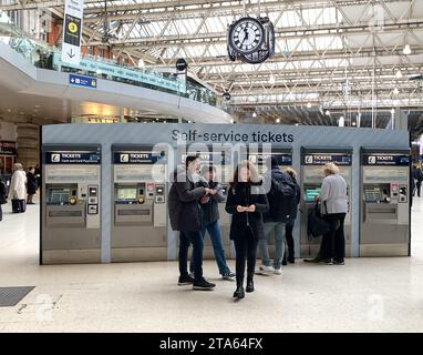 Waterloo, Londres, Royaume-Uni. 27 novembre 2023. Passagers utilisant des distributeurs automatiques de billets en libre-service à la gare de Waterloo à Londres. Les membres du syndicat des conducteurs ASLEF organiseront une autre série de grèves d’une journée entre les différents opérateurs ferroviaires entre le 2 décembre 2023 et le 8 décembre 2023. Il y aura également une interdiction des heures supplémentaires dans toutes les compagnies ferroviaires du 1 au 9 décembre 2023 dans un différend amer en cours sur les salaires et les conditions. Crédit : Maureen McLean/Alamy Live News Banque D'Images