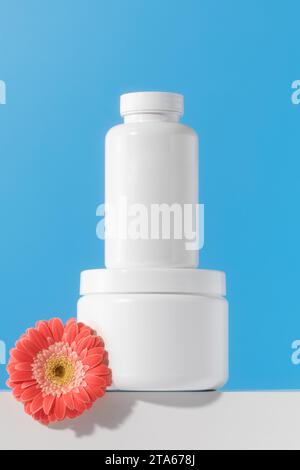 Mockup est un pot blanc avec des pilules ou des vitamines sur un podium. Vitamines pour femmes Banque D'Images