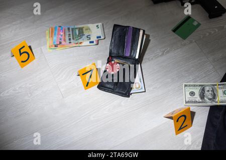 Enquête sur les lieux du crime - numérotation des preuves après le meurtre dans l'appartement. Porte-fusée, portefeuille et vêtements en laiton avec marqueurs de preuve Banque D'Images