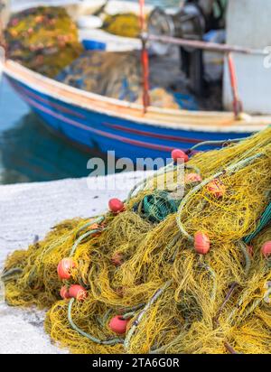 Gros plan, vue détaillée et arrière-plan des filets de pêche usagés qui ont été posés l'un sur l'autre devant un port et des bateaux de pêche dans la ba Banque D'Images