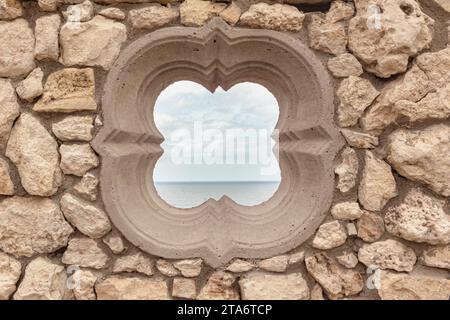 Fenêtre ronde vide - fenêtre médiévale en forme de fleur en pierre rustique avec océan et ciel derrière - Tergniet Afrique du Sud Banque D'Images