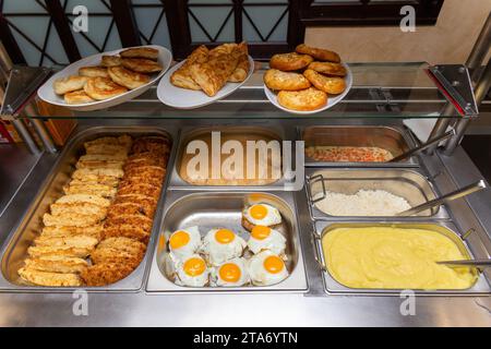 Fast food bistro, nourriture dans des plateaux en métal, salade de côtelettes garniture sur la fenêtre du café, patches avec nourriture sur le comptoir de bistro, viande et garniture dans des patches. Banque D'Images