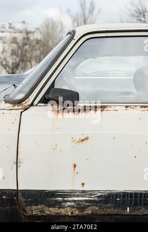 Corrosion de la tôle sur la roue de l'ancienne voiture blanche. Surface rouillée. Texture sale endommagée du sel de voirie. Arrière-plan rouillé. Protection de l'a Banque D'Images